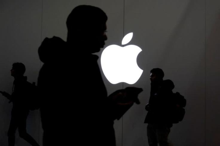 Silhouettes of people walking in front of an illuminated Apple logo, symbolizing the company’s quiet but growing ambition in AI and health innovation.
