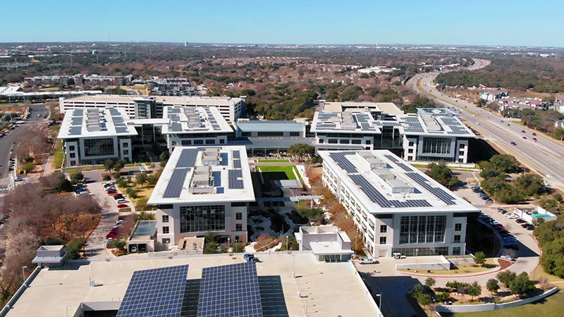 Vista aérea de las instalaciones de Apple en Houston, Texas, destacando edificios modernos con paneles solares y áreas verdes.