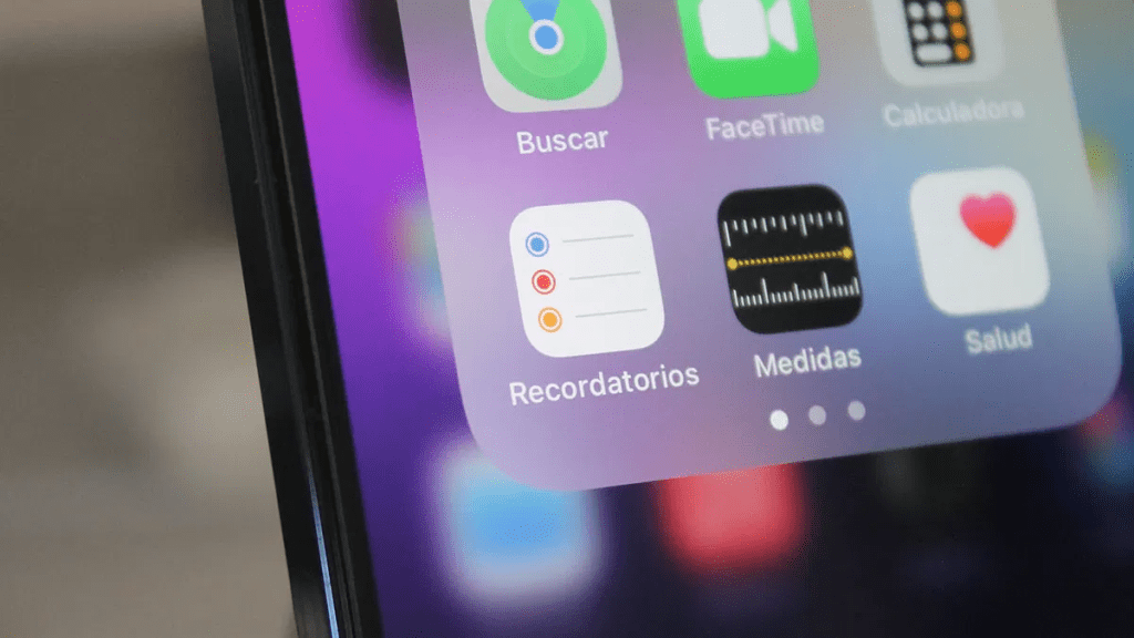 Pantalla de un iPhone mostrando una carpeta de aplicaciones que incluye los iconos de Recordatorios, Medidas, y otras aplicaciones de Apple.