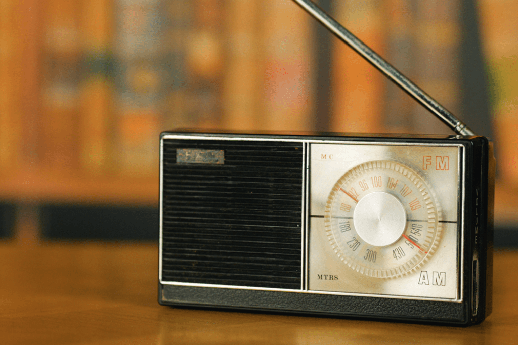 Radio AM antigua sobre una superficie de madera, con diales visibles para FM y AM.