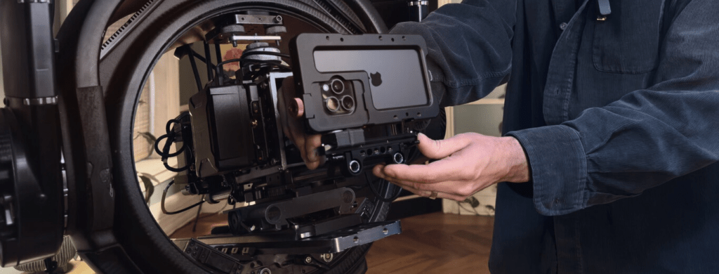 Una persona colocando un iPhone en un soporte cinematográfico avanzado, mostrando la combinación de tecnología de cine profesional y un teléfono móvil.