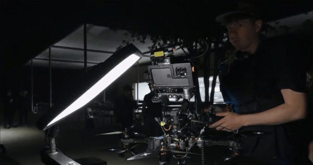 Un operador de cámara durante un rodaje nocturno, manipulando un equipo audiovisual con iluminación LED.