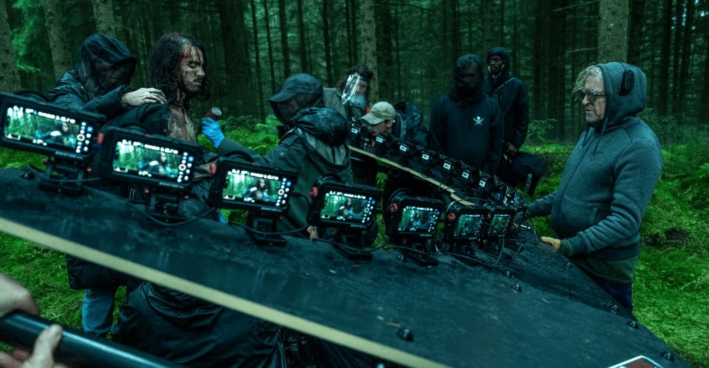 Un equipo de filmación en un bosque, utilizando múltiples pantallas montadas en un soporte mientras graban una escena.