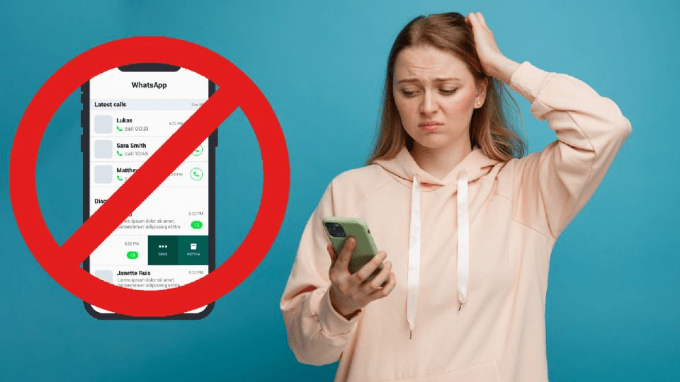 Una mujer preocupada sostiene un teléfono móvil con una pantalla que presenta el logo de WhatsApp tachado, frente a un fondo azul.