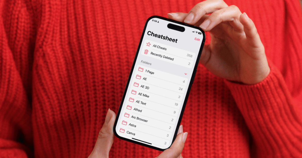 Una persona sostiene un iPhone mostrando la interfaz de la app Cheatsheet, con una lista de notas y carpetas.