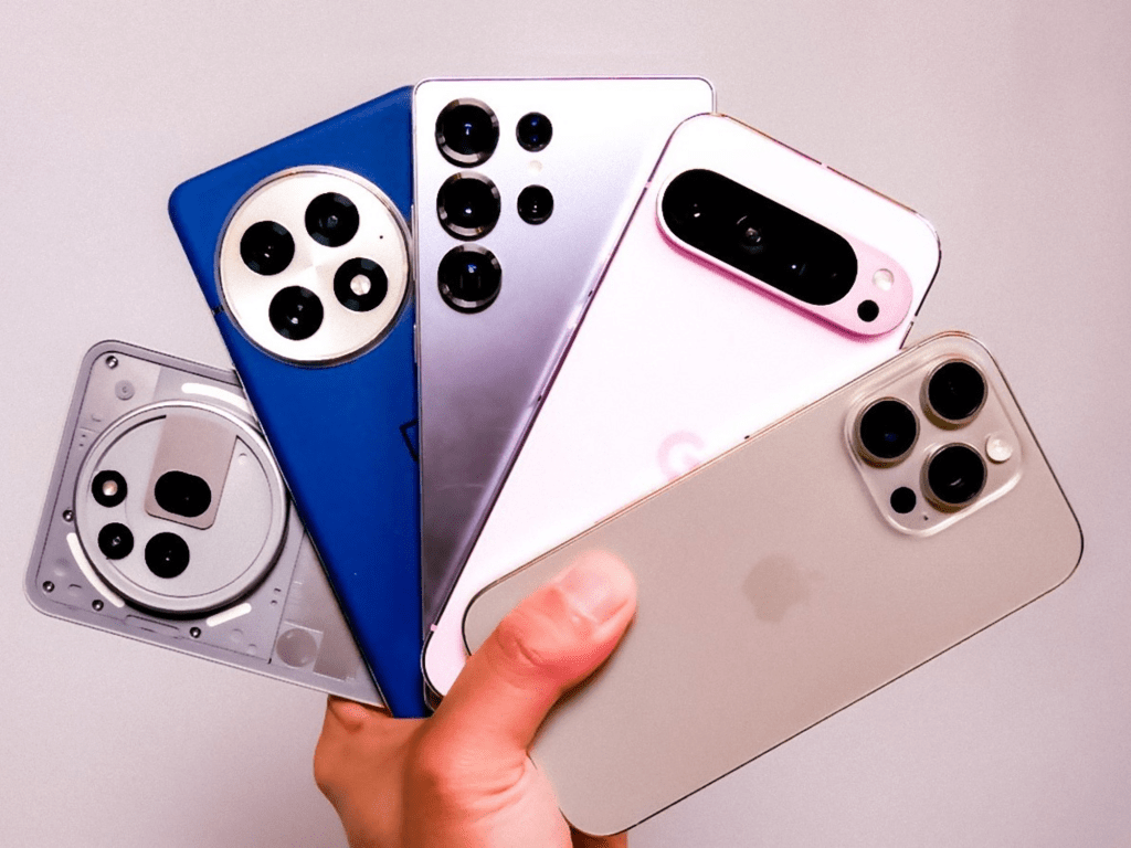 Varias smartphones en una mano, mostrando diferentes modelos y colores, incluyendo un dispositivo de Apple.