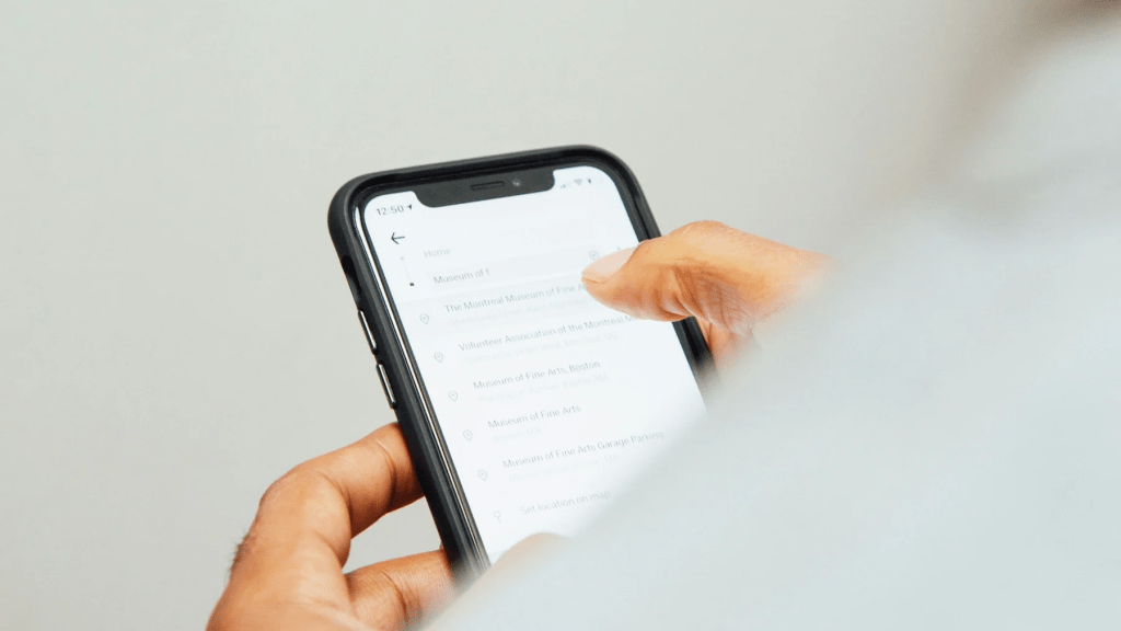Usuario interactuando con un teléfono móvil mostrando una lista de museos.