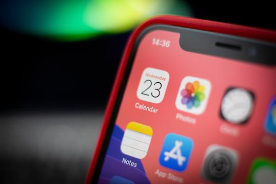 Primer plano de la pantalla de un iPhone mostrando la fecha, hora, y aplicaciones como Calendario, Fotos, Notas y App Store.