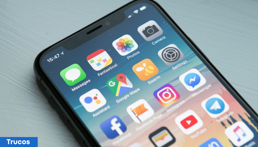 Pantalla de un iPhone mostrando varias aplicaciones, incluyendo Mensajes, Fantastical, Fotos y Ajustes, con un fondo de colores suaves.