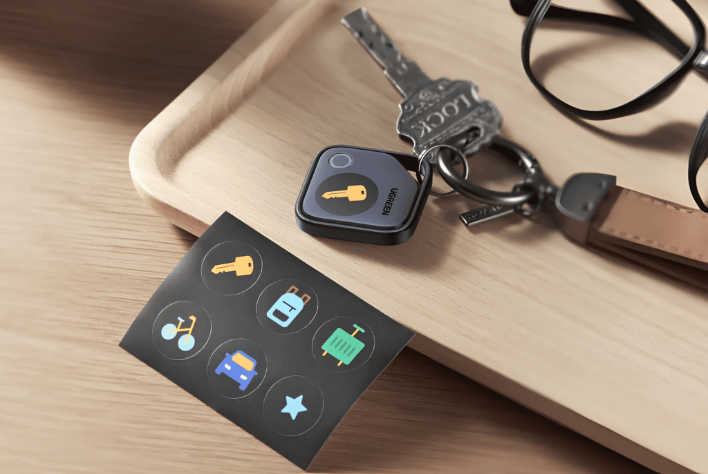 Llaves y un dispositivo rastreador sobre una bandeja de madera, junto a una tarjeta con íconos de objetos como una bici, maleta y coche.