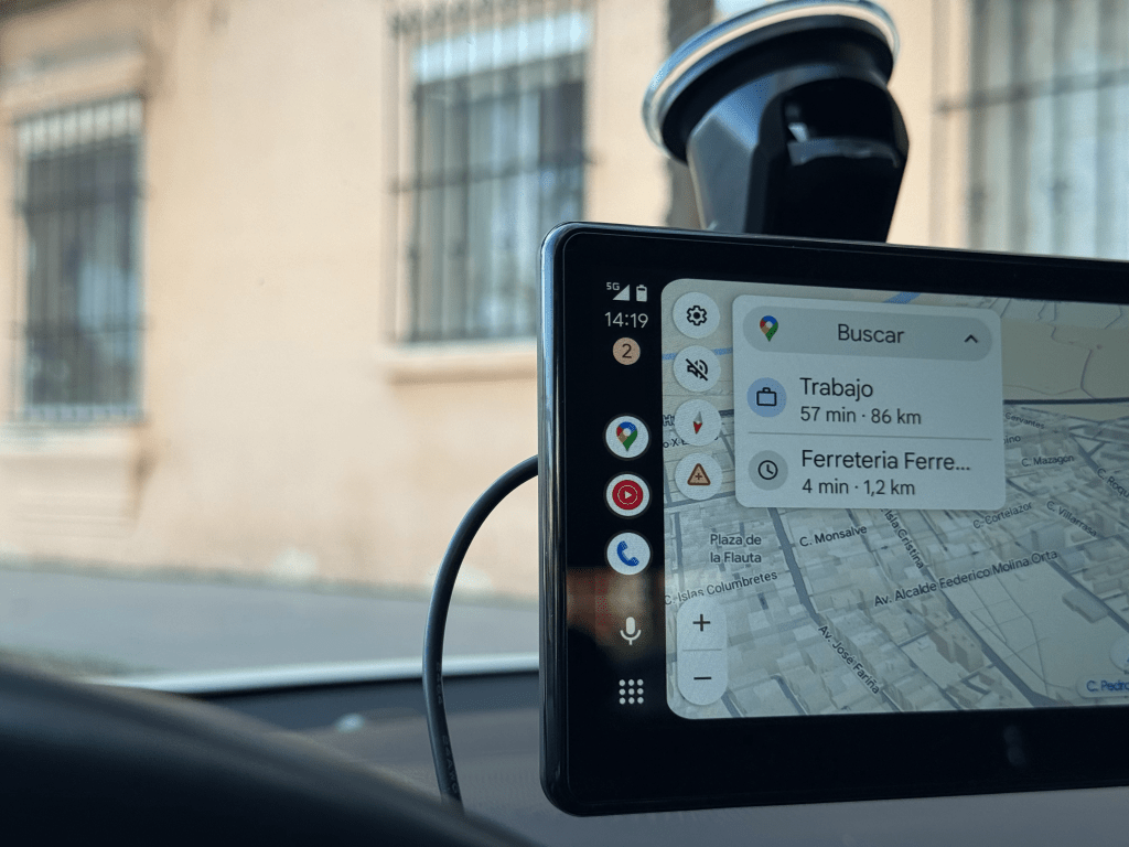 Interfaz de navegación GPS mostrando rutas hacia trabajo y ferretería, con información de distancia y tiempo estimado. Vista interior de un vehículo.