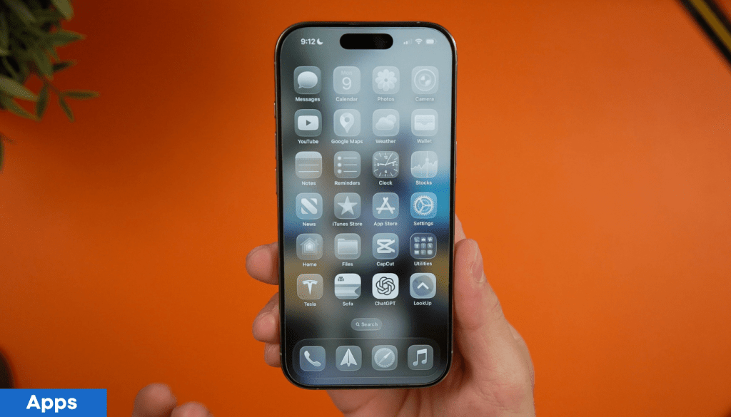 Un usuario sosteniendo un iPhone con la pantalla mostrando varias aplicaciones sobre un fondo naranja.