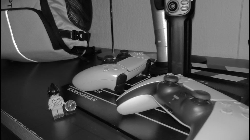 Controladores de videojuegos y LEGO sobre una superficie negra con una mochila al fondo.