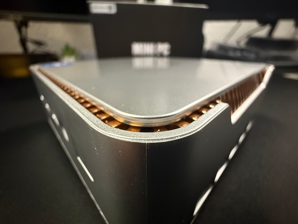 Vista lateral de un dispositivo electrónico con un diseño metálico y bordes redondeados sobre una superficie oscura.